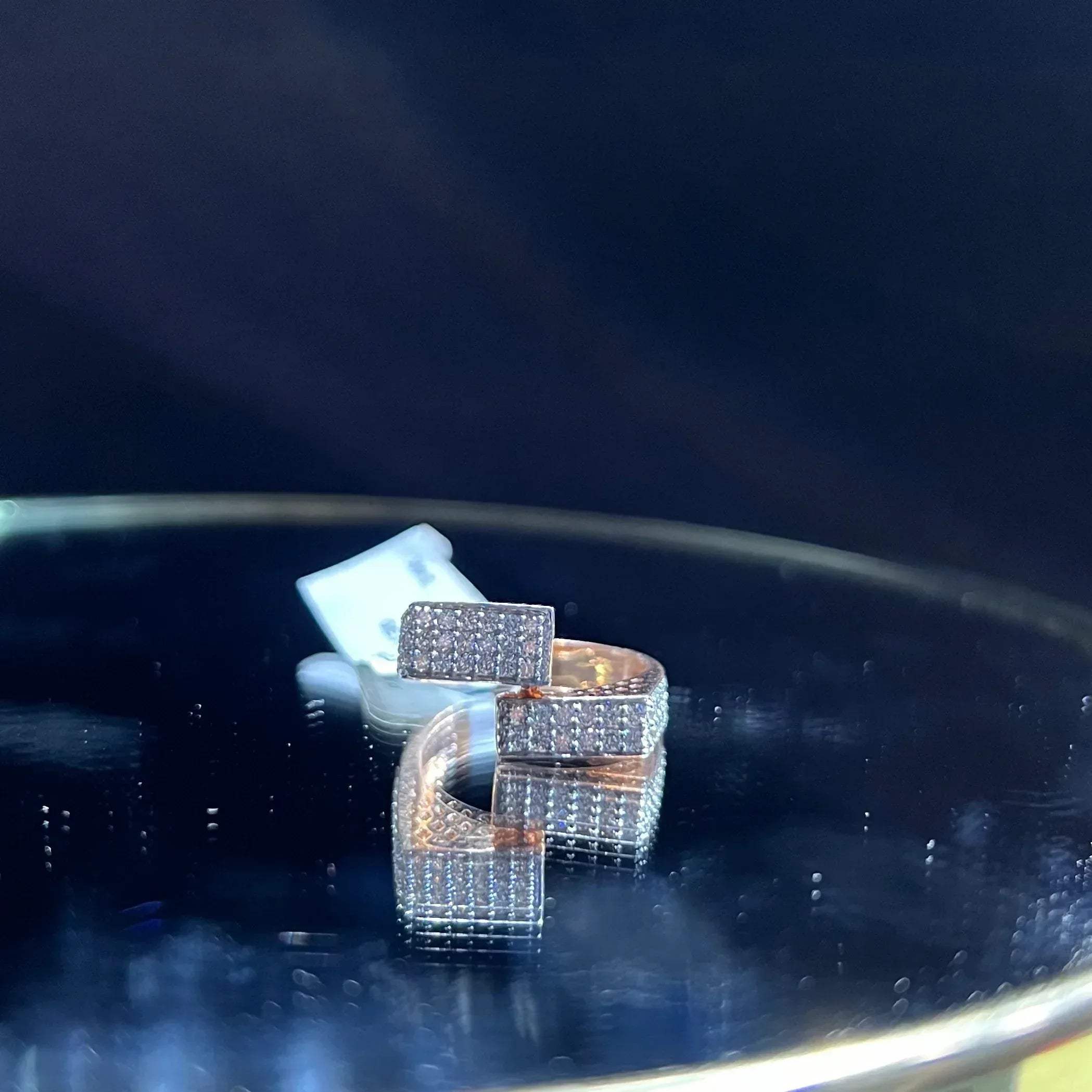 A man's hand displaying a 14K gold diamond ring with a solid band and a small diamond inlay on the top surface.