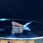 A reflective surface displaying a 14K gold diamond ring with a solid band and a small diamond inlay on the top surface.