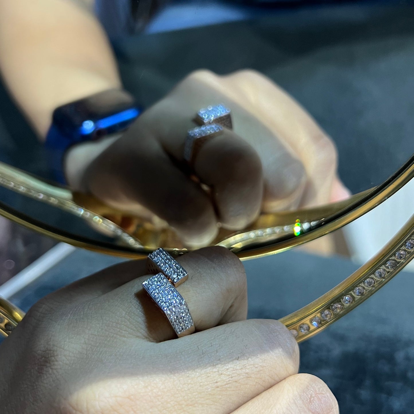 Two man's hand displaying two gold diamond ring with a solid band and a small diamond inlay on the top surface.