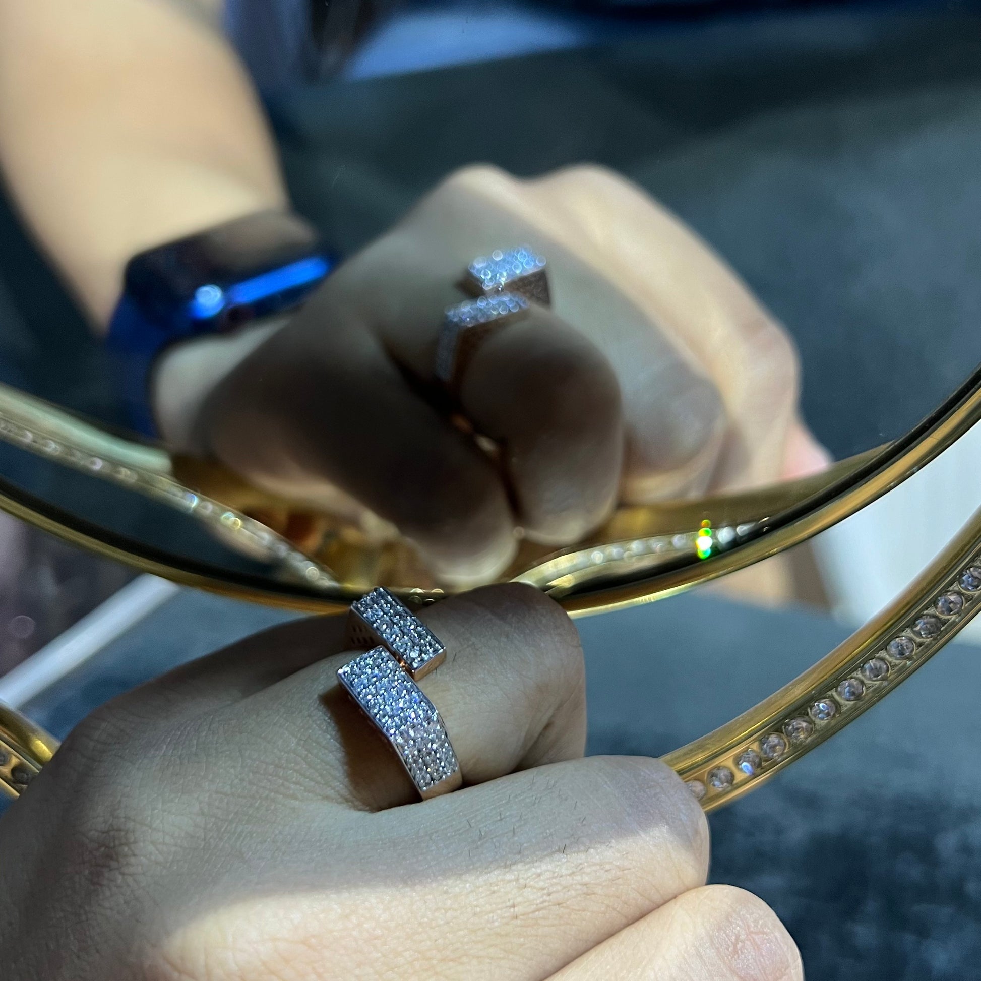 Two man's hand displaying two gold diamond ring with a solid band and a small diamond inlay on the top surface.