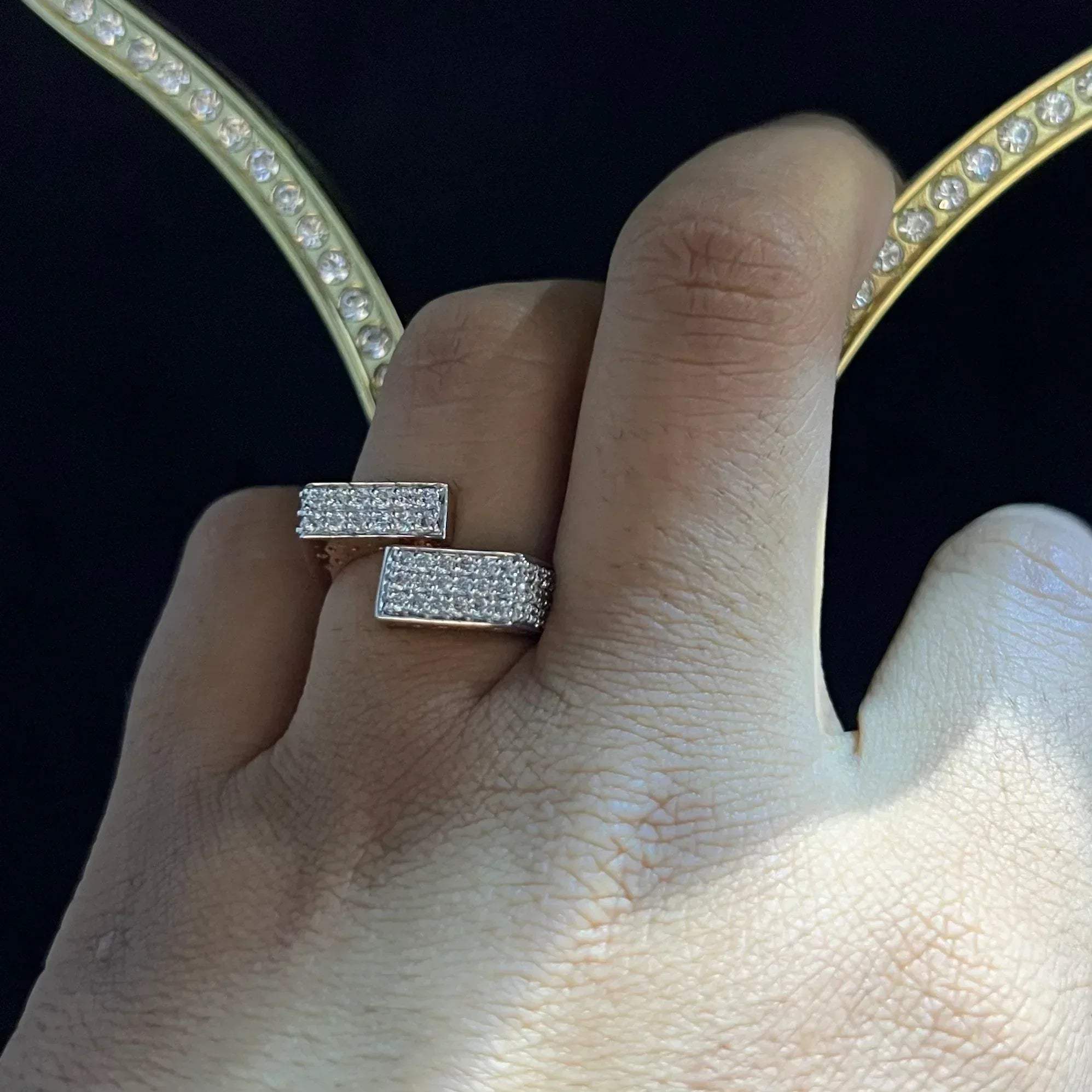 A man's hand displaying a 14K gold diamond ring with a solid band and a small diamond inlay on the top surface.
