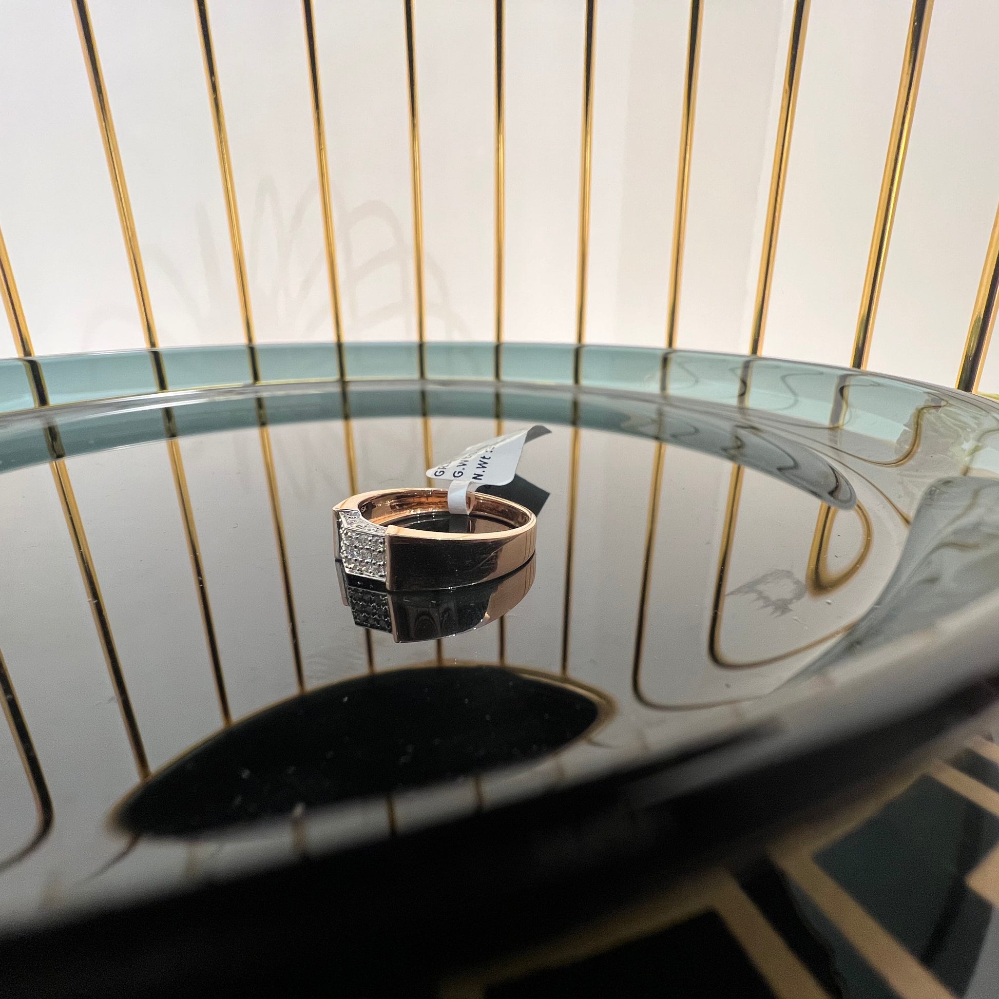 A man's hand holding a gold-banded ring with a large, clear crystal on top, and a smaller, real diamond on the band.