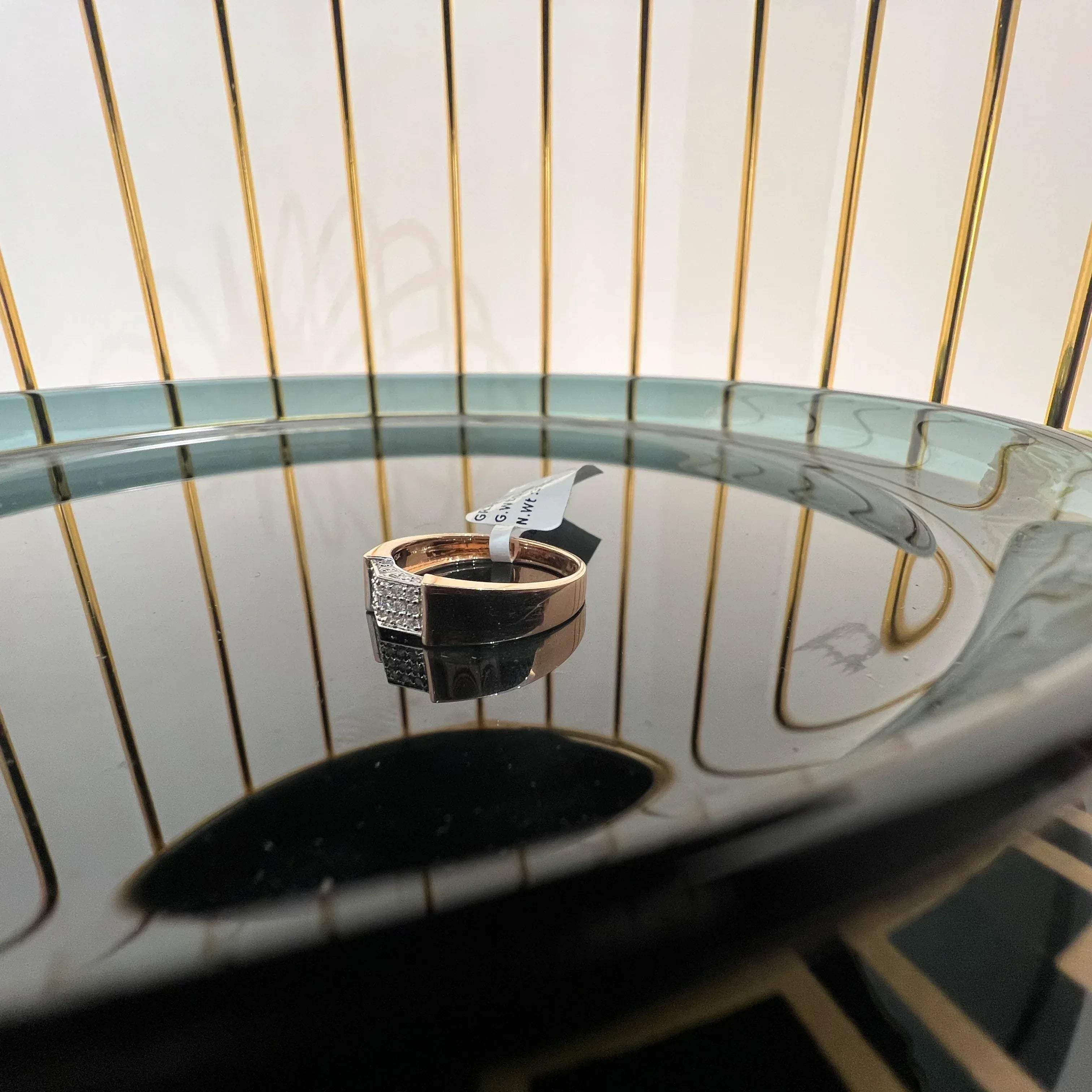 A man's hand holding a gold-banded ring with a large, clear crystal on top, and a smaller, real diamond on the band.