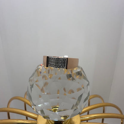 A man's hand holding a gold-banded ring with a large, clear crystal on top, and a smaller, real diamond on the band.