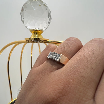 A man's hand holding a gold-banded ring with a large, clear crystal on top, and a smaller, real diamond on the band.
