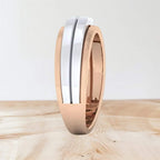 Two-tone diamond ring with rose gold and white gold finish on a wooden surface