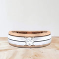 Two-tone ring with a diamond on a wooden surface