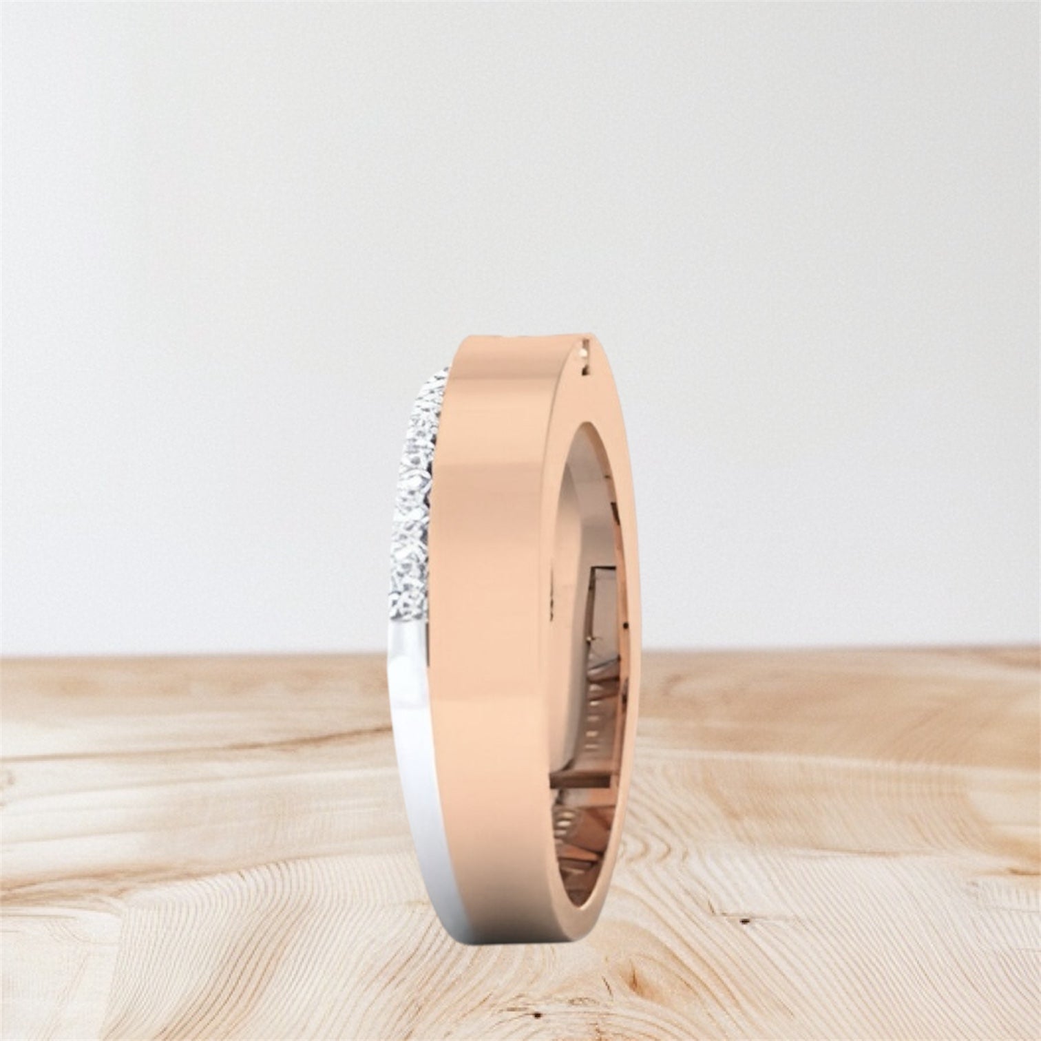 Rose gold ring with small diamonds on a light wooden surface.