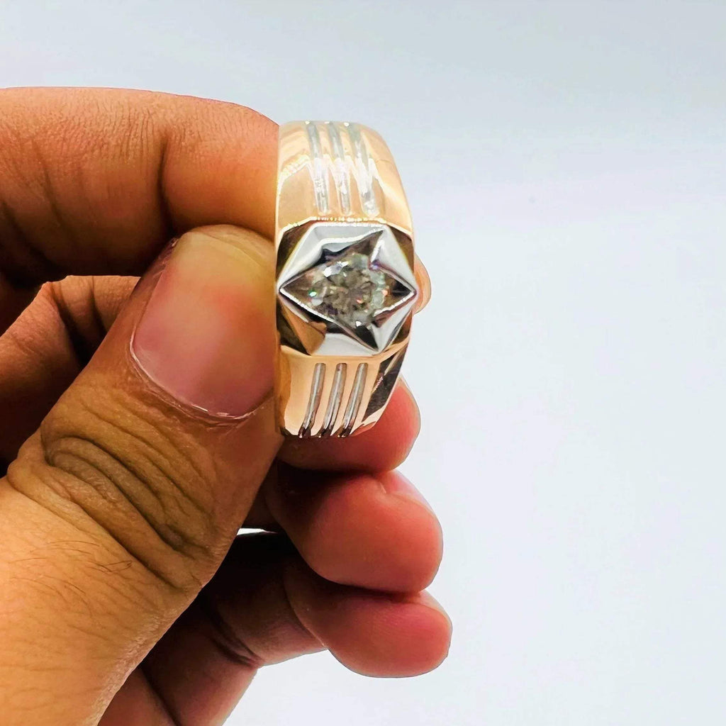 A man's hand displaying a gold solitaire diamond ring hold by his two fingers from front side.