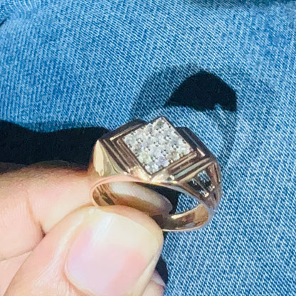 A man's hand holding a diamond ring with a rose gold band, featuring a solitaire diamond on top.