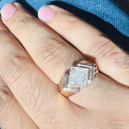 A man's hand holding a diamond ring with a rose gold band, featuring a solitaire diamond on top.