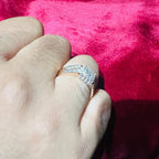 A man's hand displaying a gold diamond ring with a solid band and a small diamond inlay on the top surface.