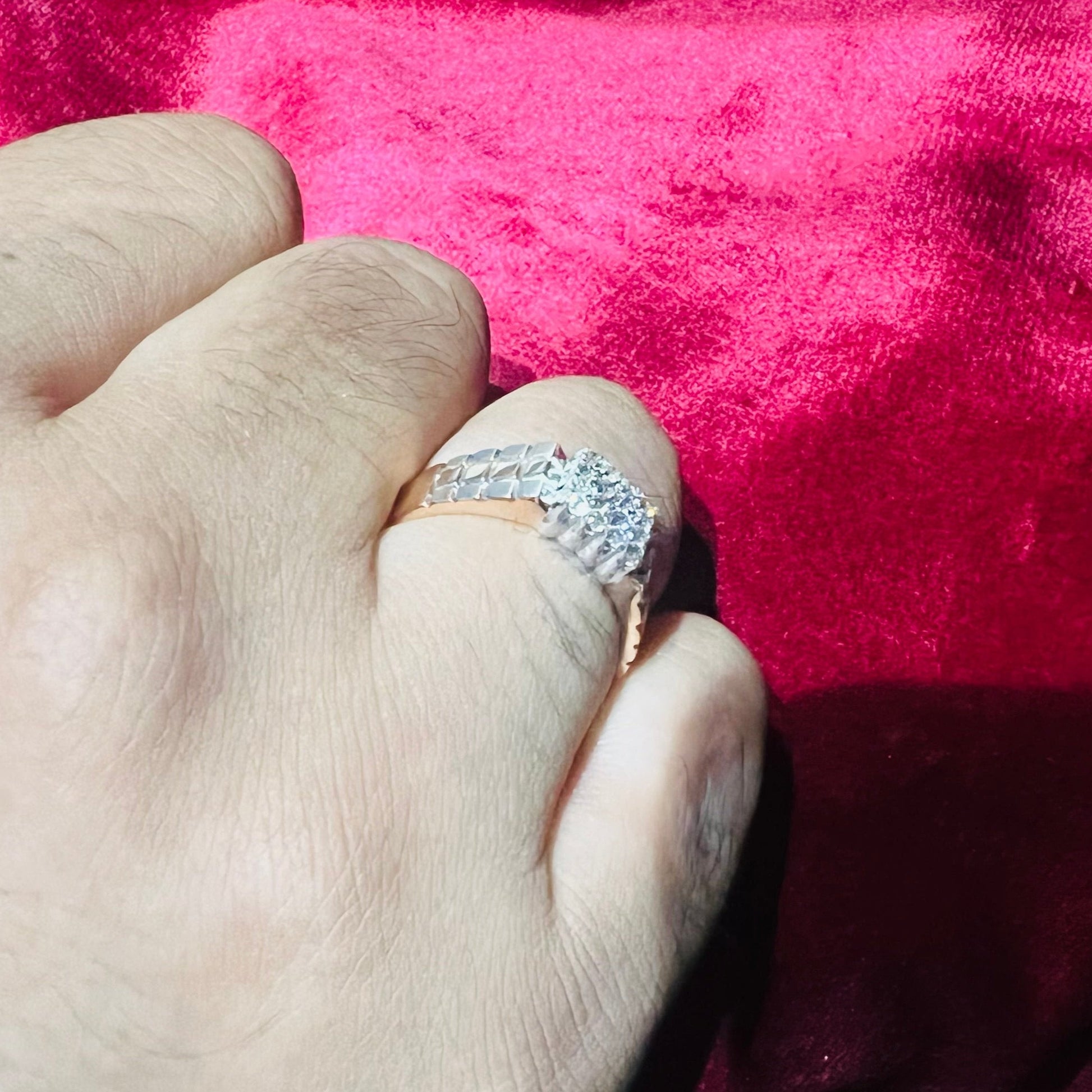A man's hand displaying a gold diamond ring with a solid band and a small diamond inlay on the top surface.