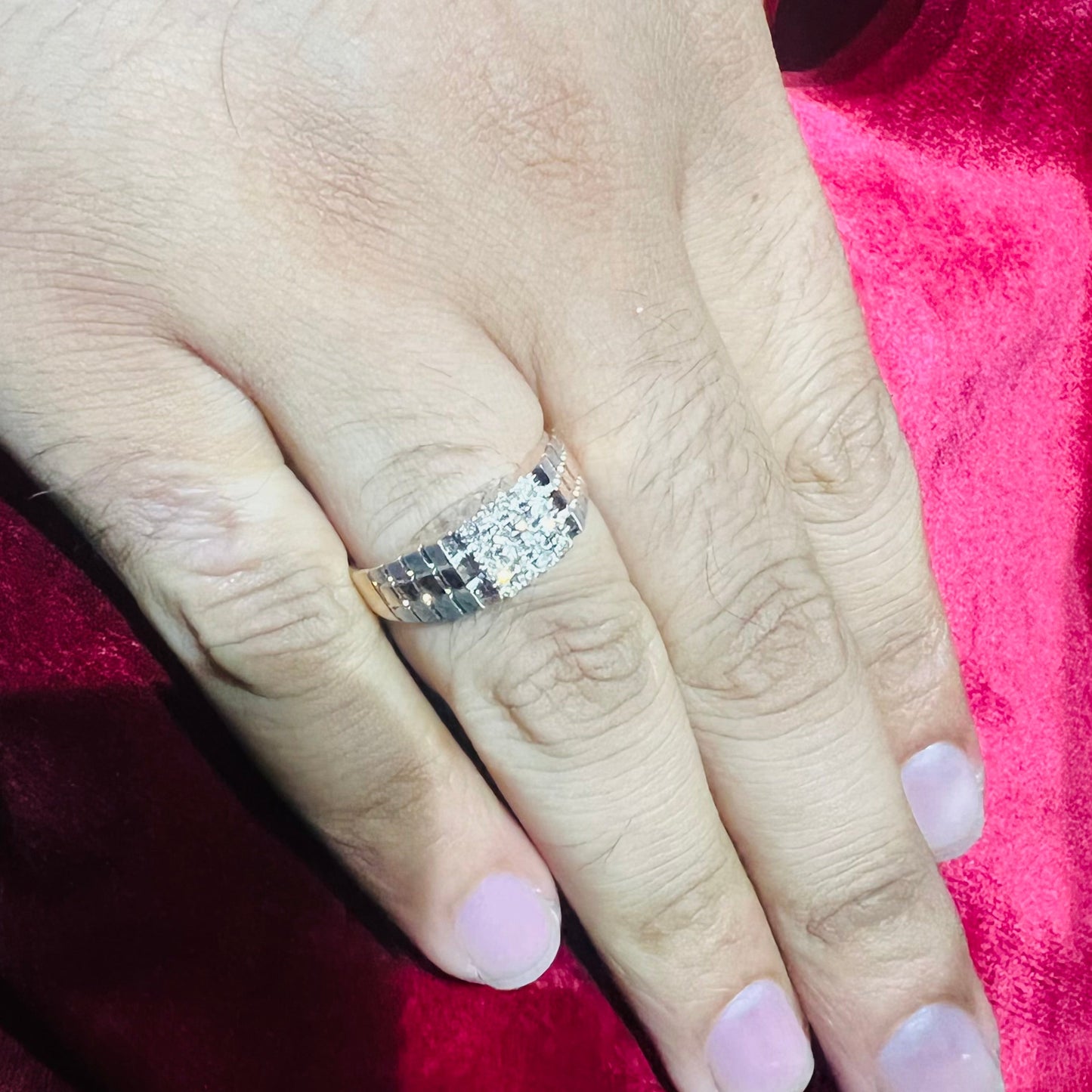 A man's hand displaying a gold diamond ring with a solid band and a small diamond inlay on the top surface.