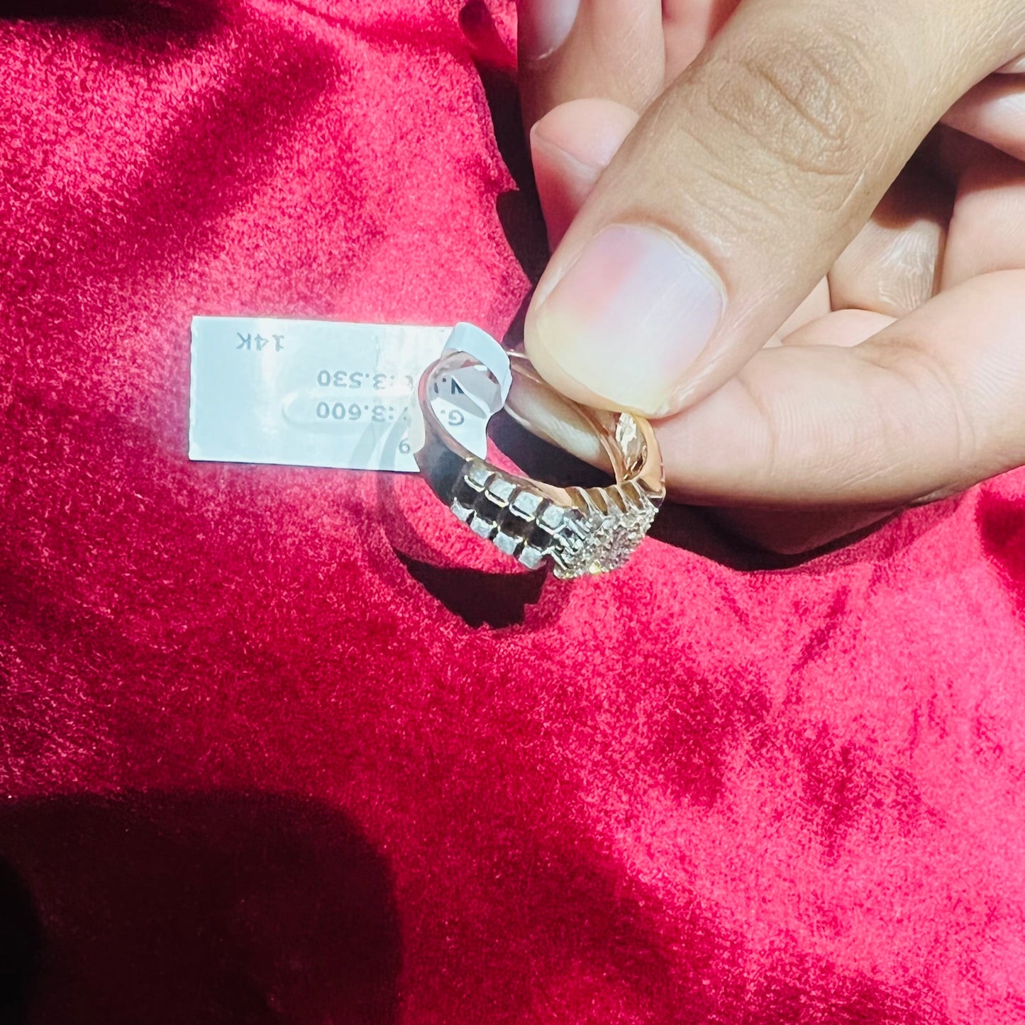 A man's hand displaying a gold diamond ring with a solid band and a small diamond inlay on the top surface.