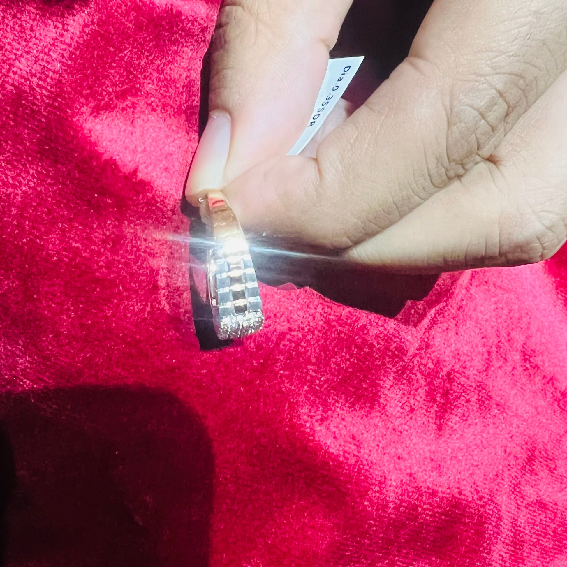 A man's hand displaying a gold diamond ring with a solid band and a small diamond inlay on the top surface.