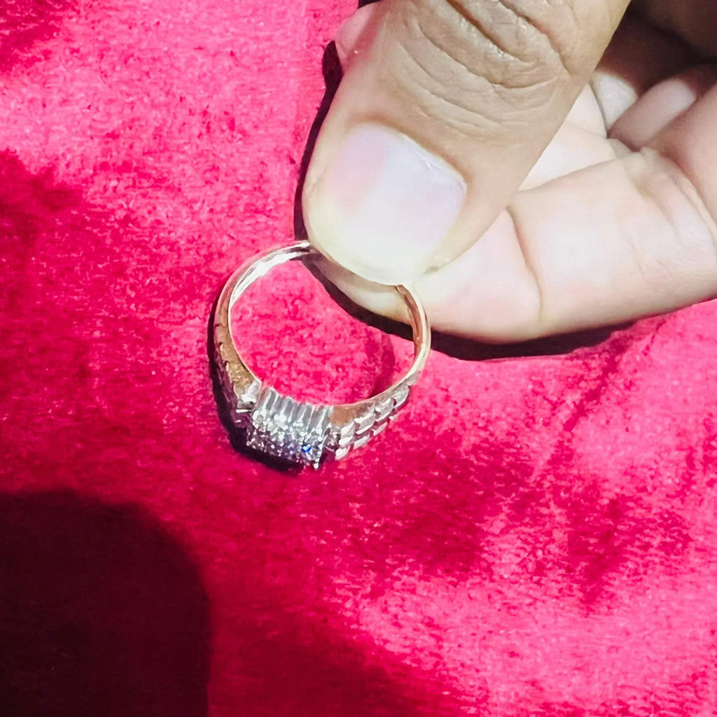 A man's hand displaying a gold diamond ring with a solid band and a small diamond inlay on the top surface.