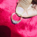 A man's hand displaying a gold diamond ring with a solid band and a small diamond inlay on the top surface.