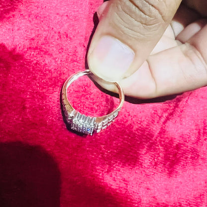 A man's hand displaying a gold diamond ring with a solid band and a small diamond inlay on the top surface.