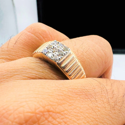 A man's hand holding a gold diamond ring with a solid gold band and a series of round cut diamonds set on top.