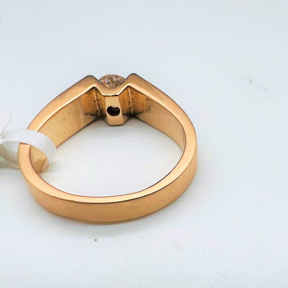 A man's solitaire diamond ring with a gold band displayed on a white surface.