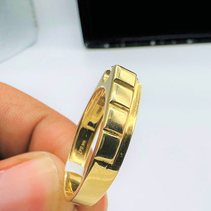 A gold band ring with a solitaire round-cut diamond set on top, held between fingers shown from vertical side.