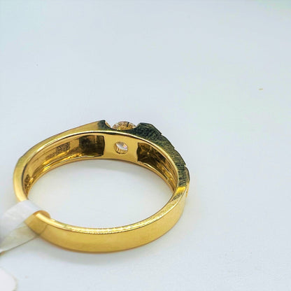 A gold band ring with a solitaire round-cut diamond set on top displayed on a white surface.