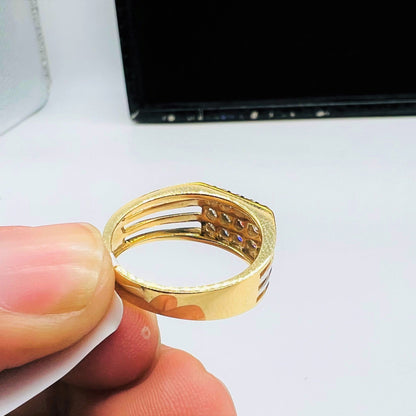 A man's hand displaying a gold band ring with smaller round-cut diamonds from back side.