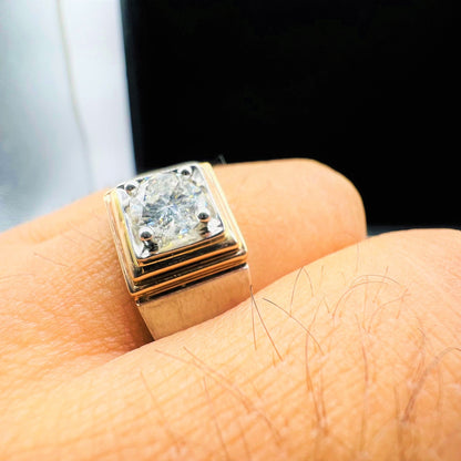 A man's hand holding a solitaire diamond ring with a gold band.