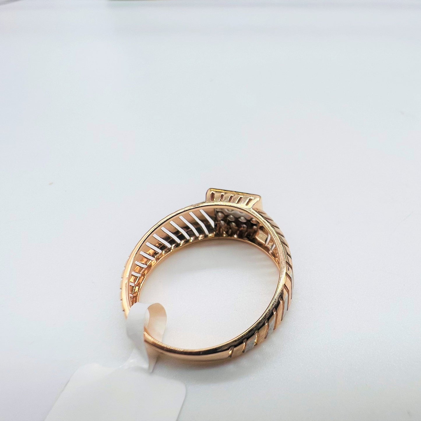 A top view of a gold diamond ring with round cut diamonds set in a square shape displayed on a white surface.