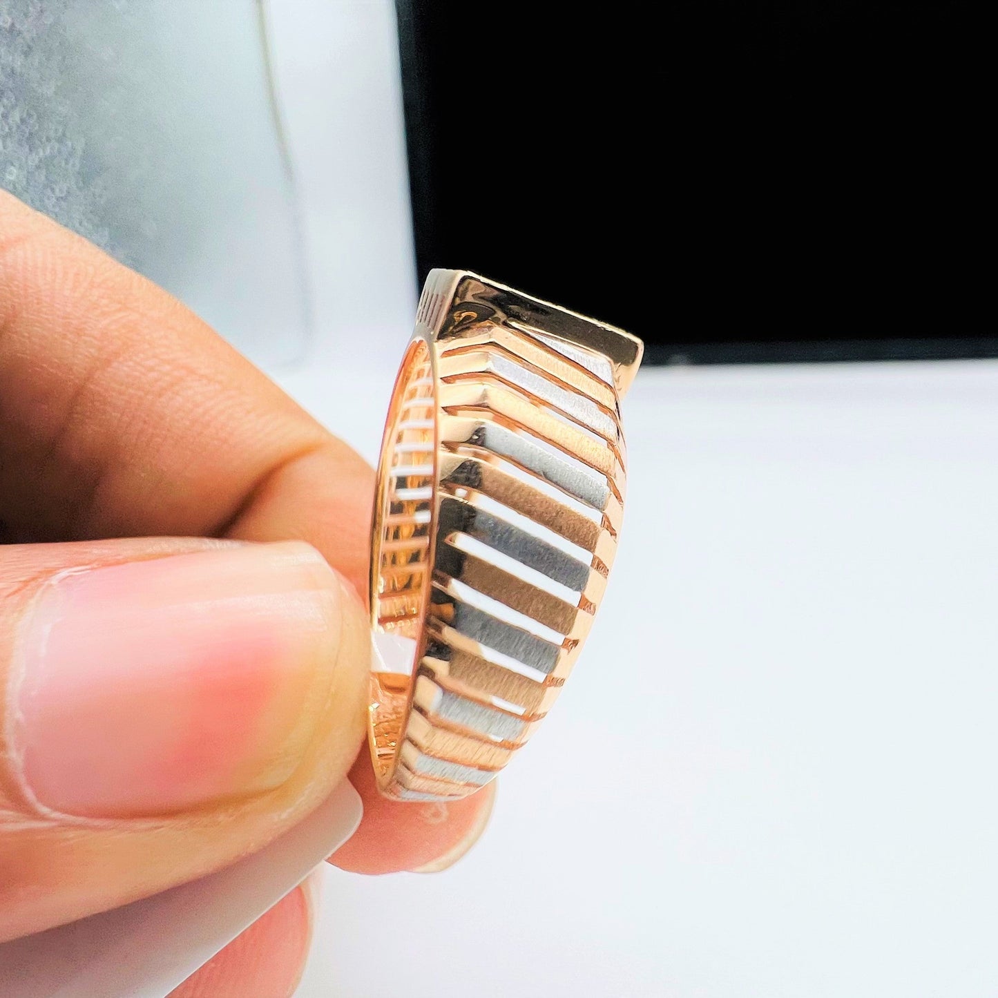 A man's hand displaying a gold diamond ring with round cut diamonds set in a square shape from the side.