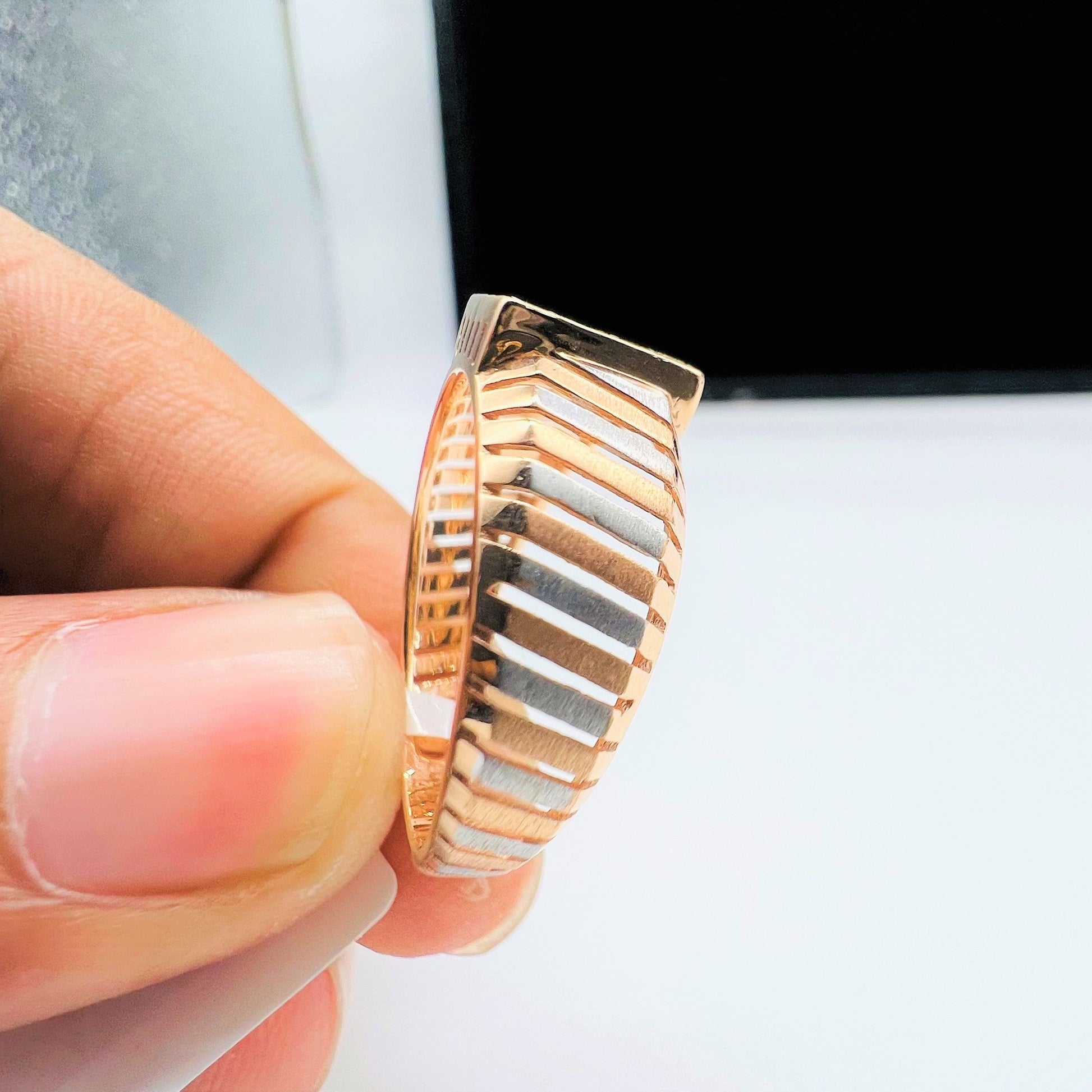 A man's hand displaying a gold diamond ring with round cut diamonds set in a square shape from the side.