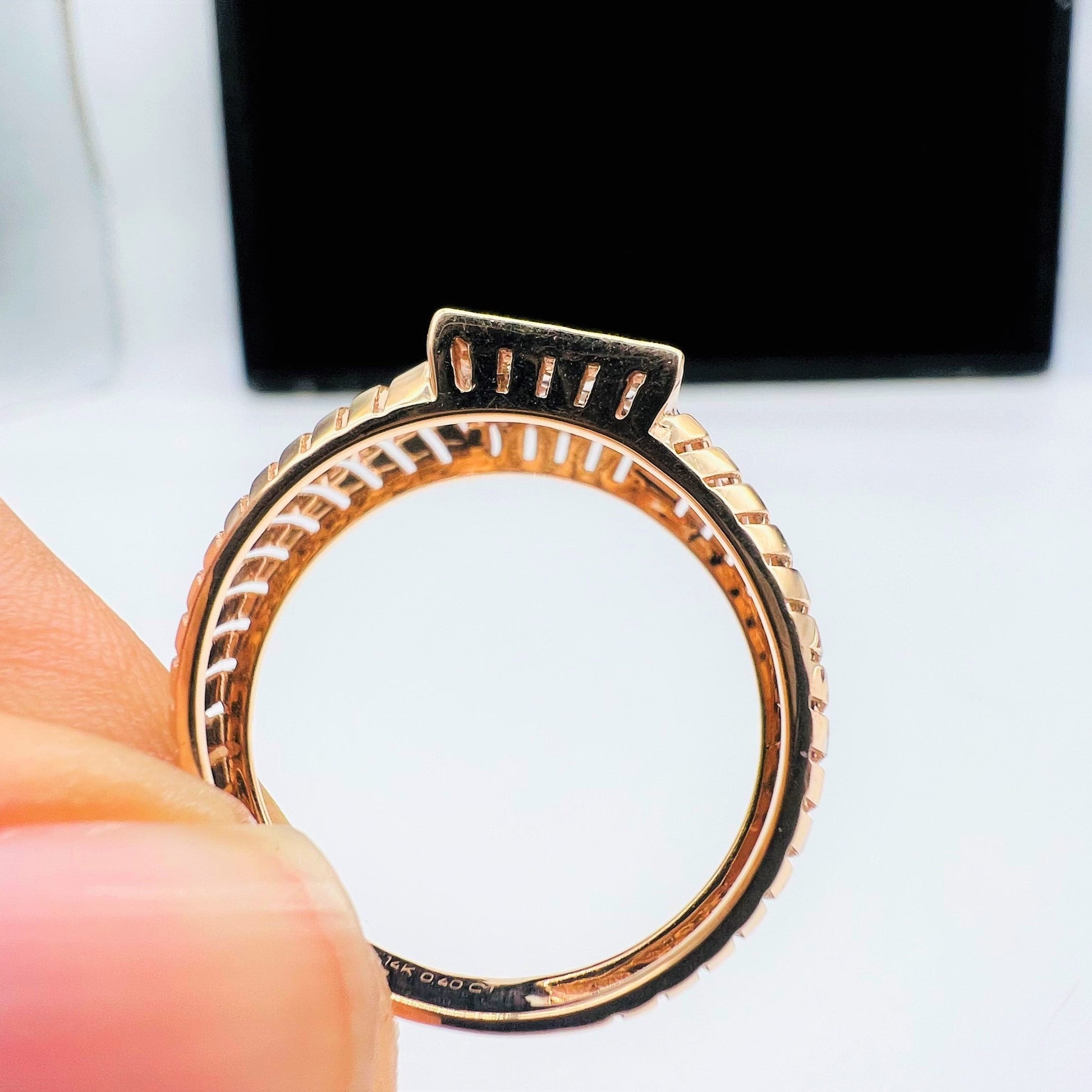 A man's hand displaying a gold diamond ring with round cut diamonds set in a square shape from the side.