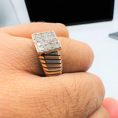 A man's hand displaying a gold diamond ring with round cut diamonds set in a square shape.