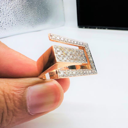 A man's hand displaying a gold diamond ring with a large square shape with round cut diamonds on top.