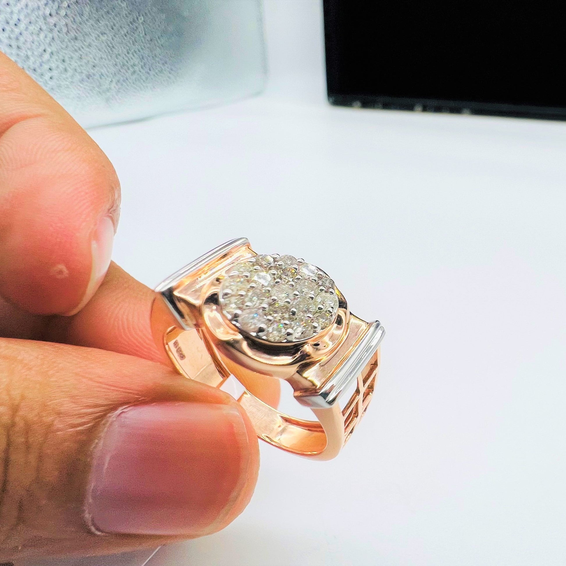 A man's hand displaying a gold band ring with round-cut diamonds set in the band.