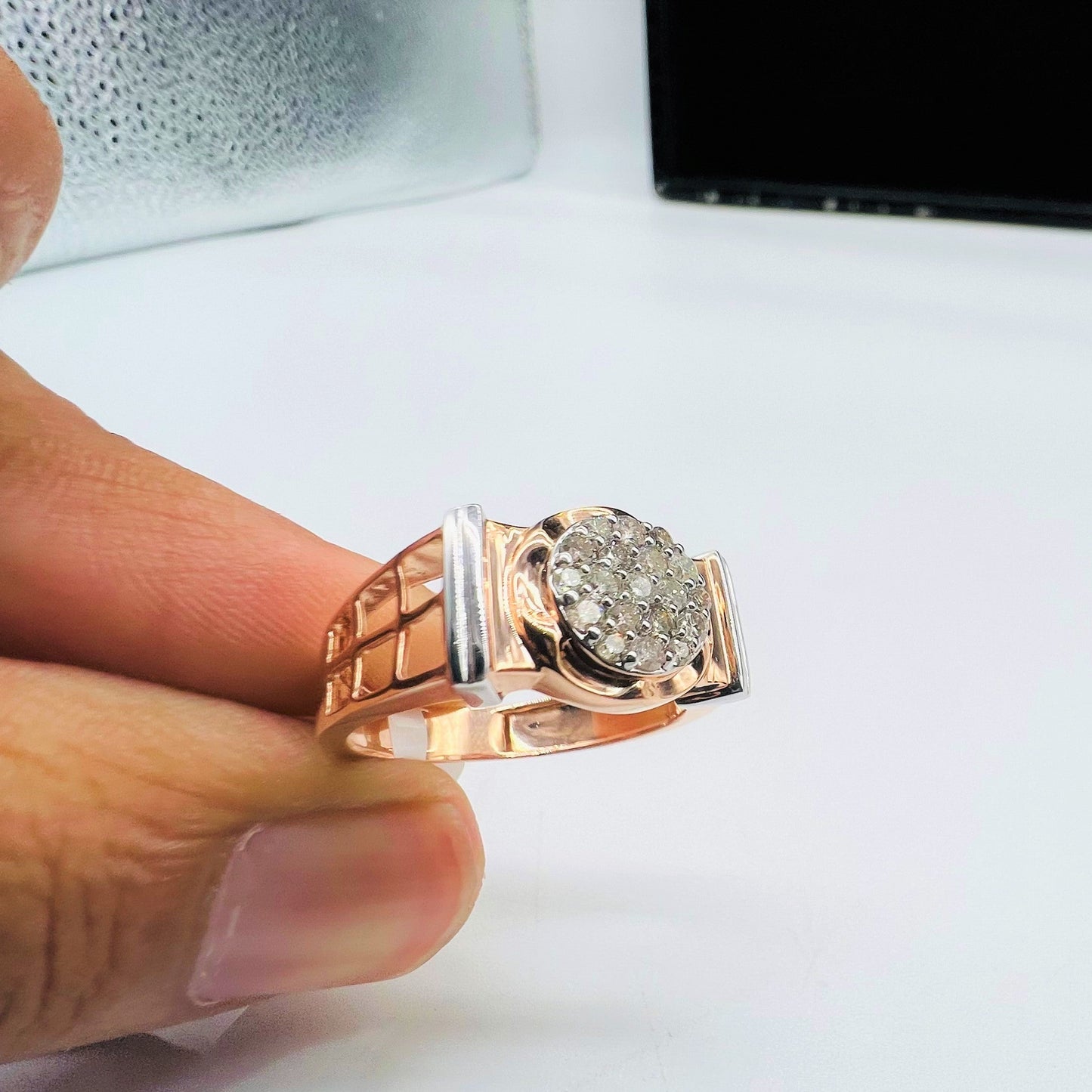 A man's hand displaying a gold band ring with round-cut diamonds set in the band.