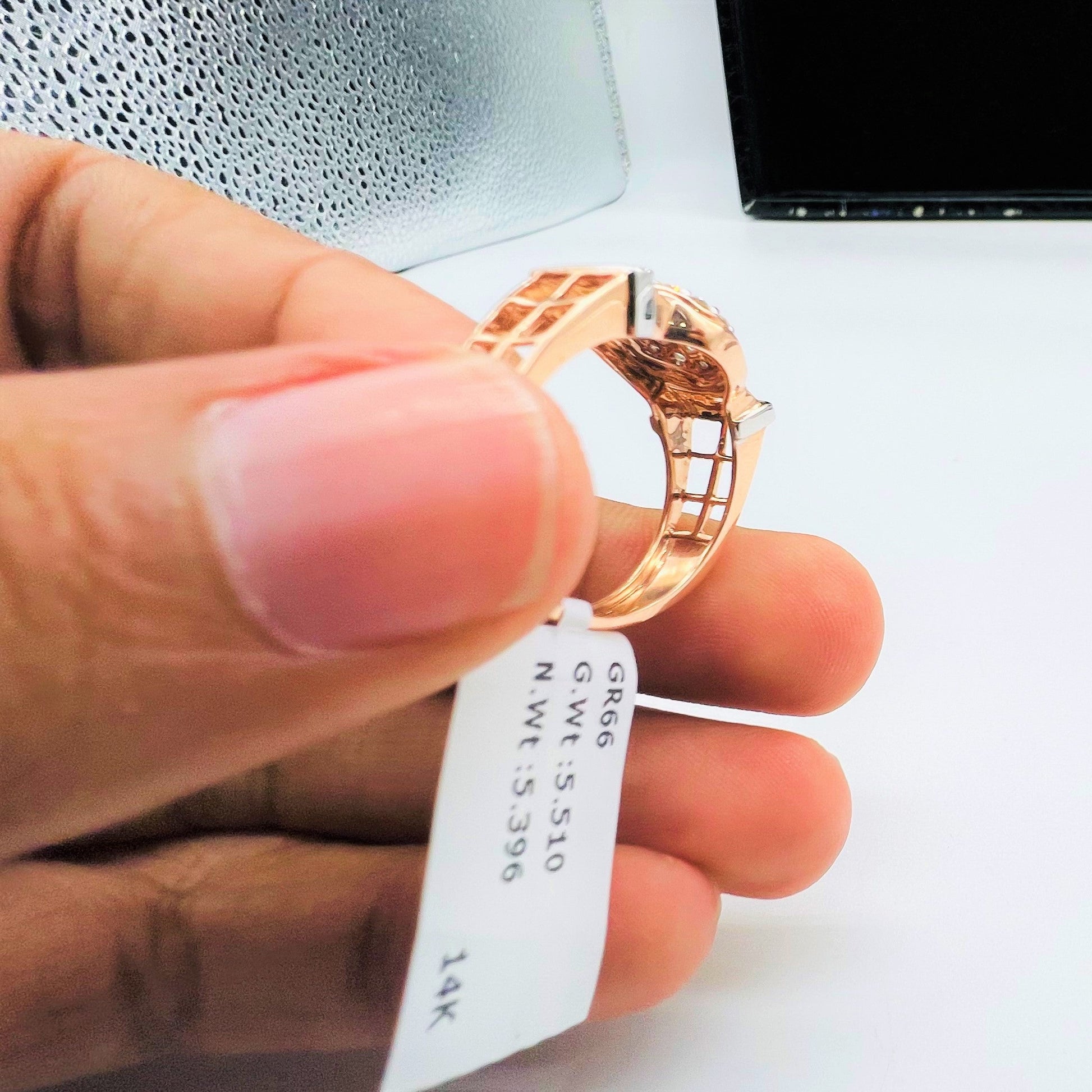 A man's hand displaying a gold band ring with round-cut diamonds set in the band.