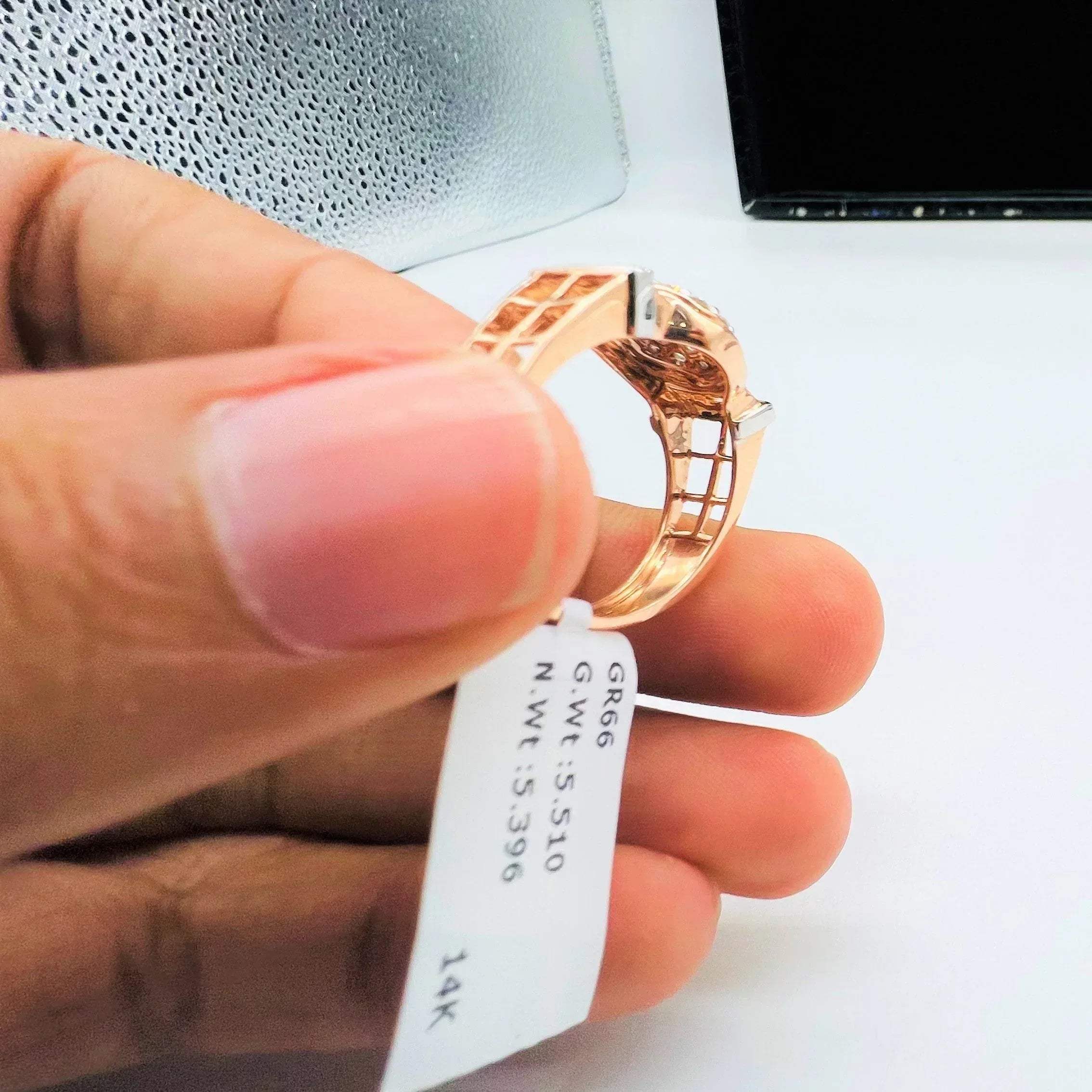 A man's hand displaying a gold band ring with round-cut diamonds set in the band.