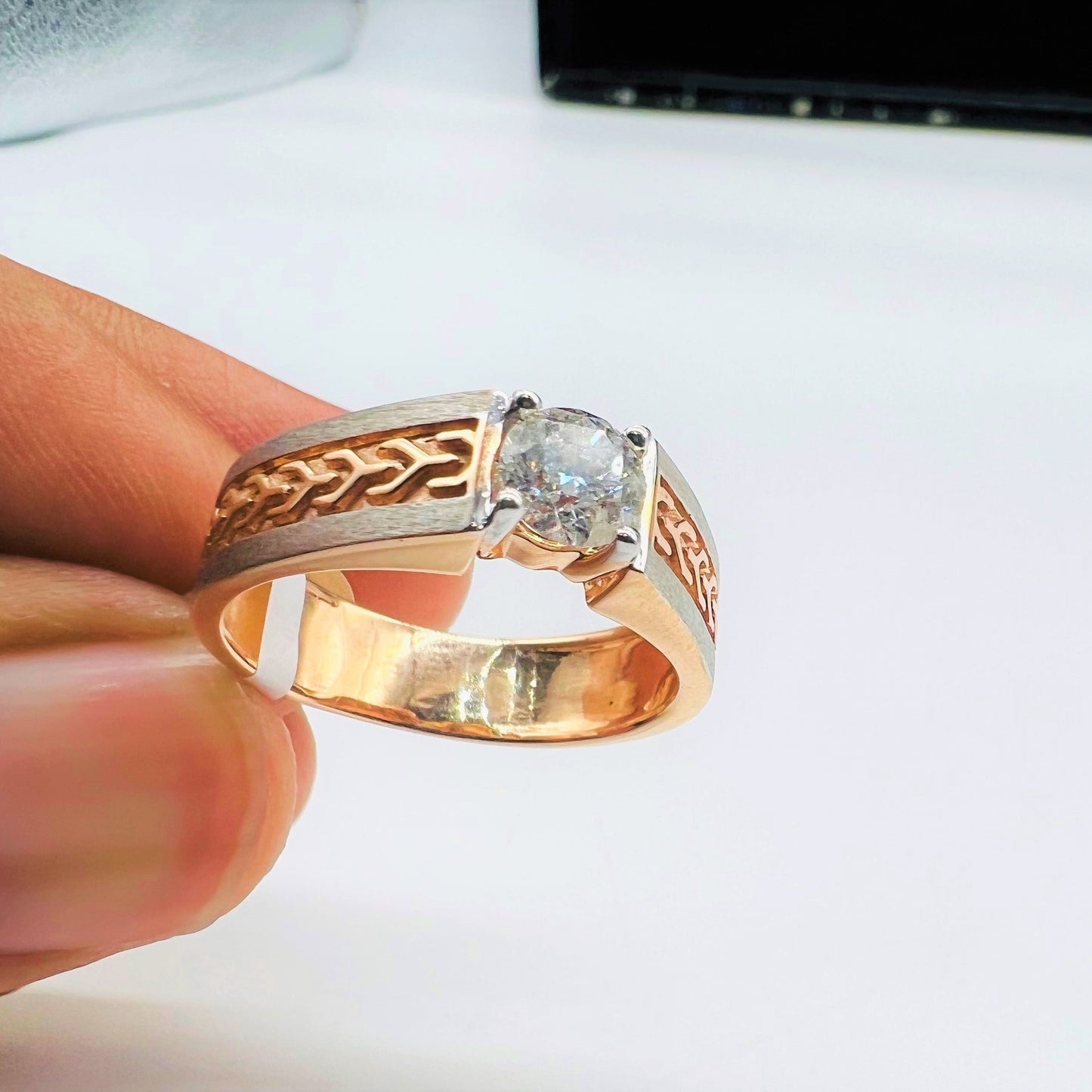 A man's hand displaying a gold band ring with round-cut diamond set in the band.