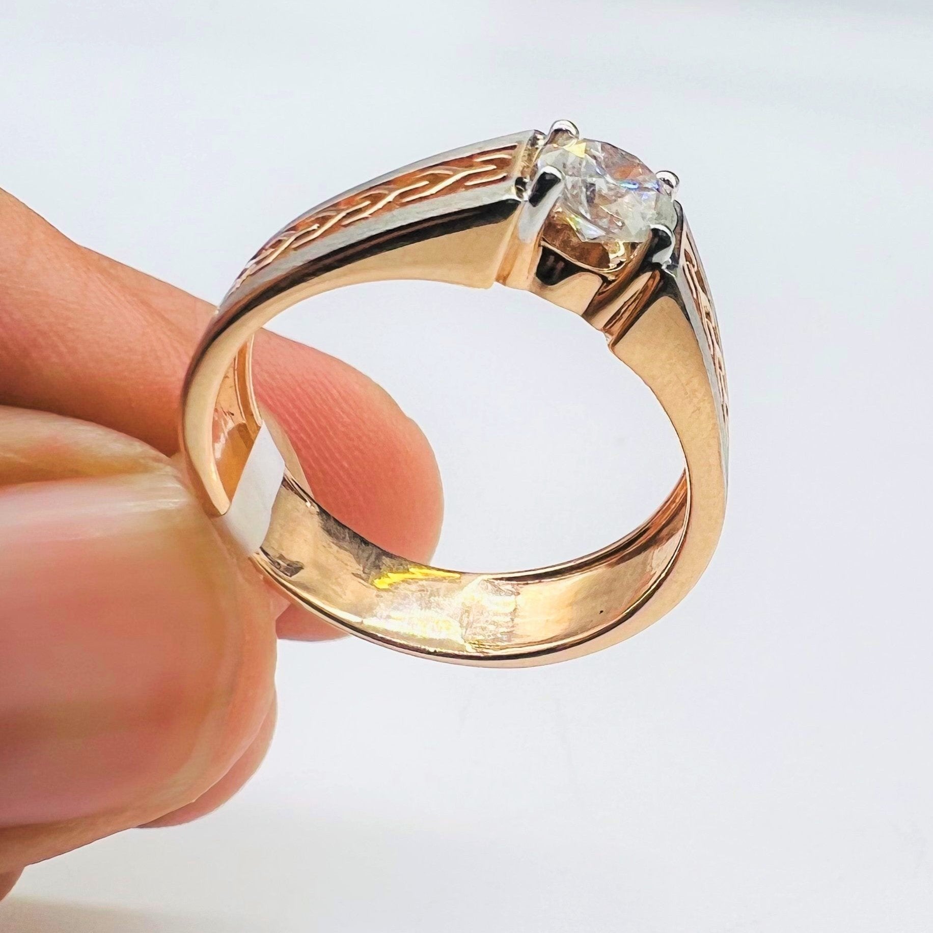 A man's hand displaying a gold band ring with round-cut diamond set in the band.