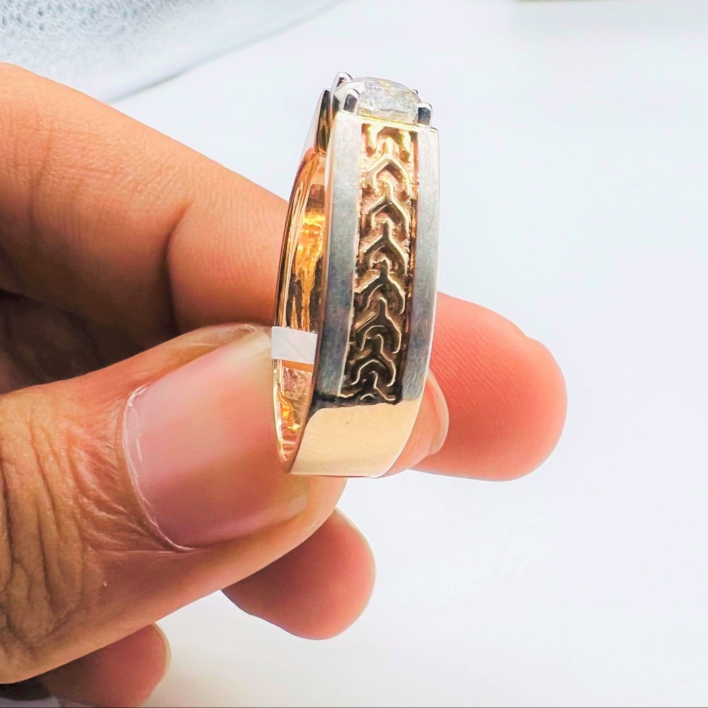 A man's hand displaying a gold band ring with round-cut diamond set in the band.