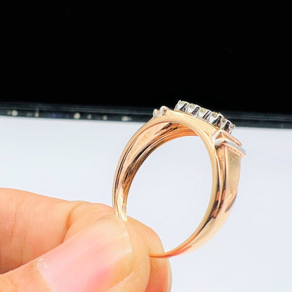 A man's hand displaying a gold diamond ring with round cut diamonds.
