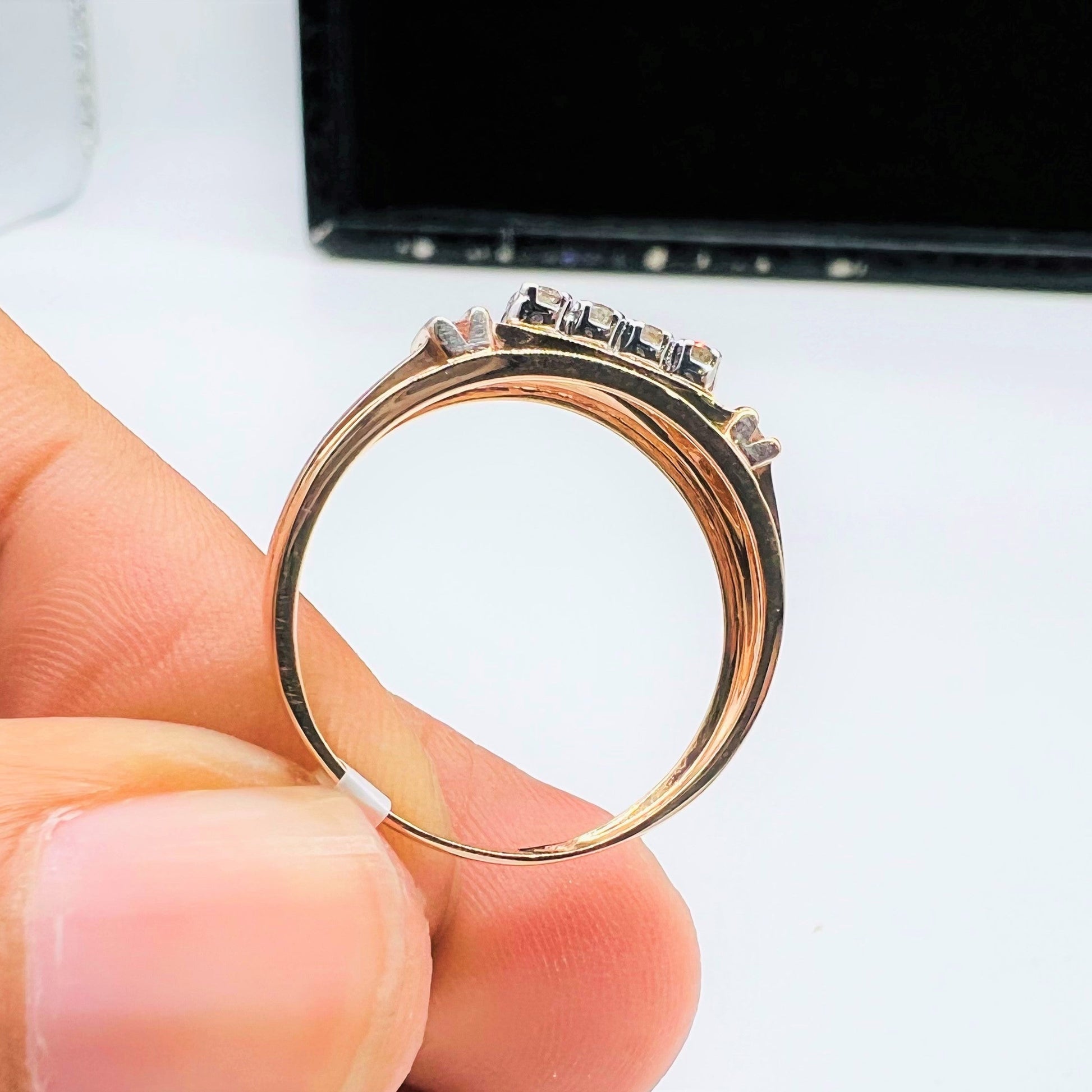 A man's hand displaying a gold diamond ring with round cut diamonds from the side.