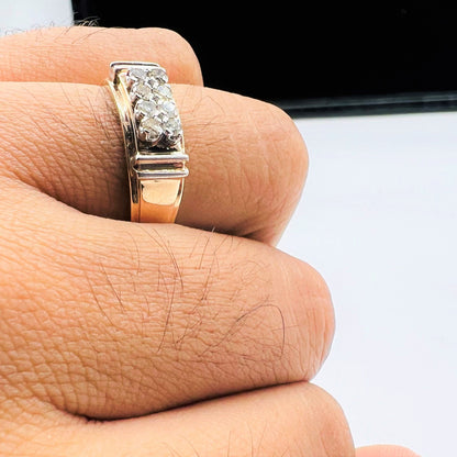 A man's hand displaying a gold diamond ring with round cut diamonds.