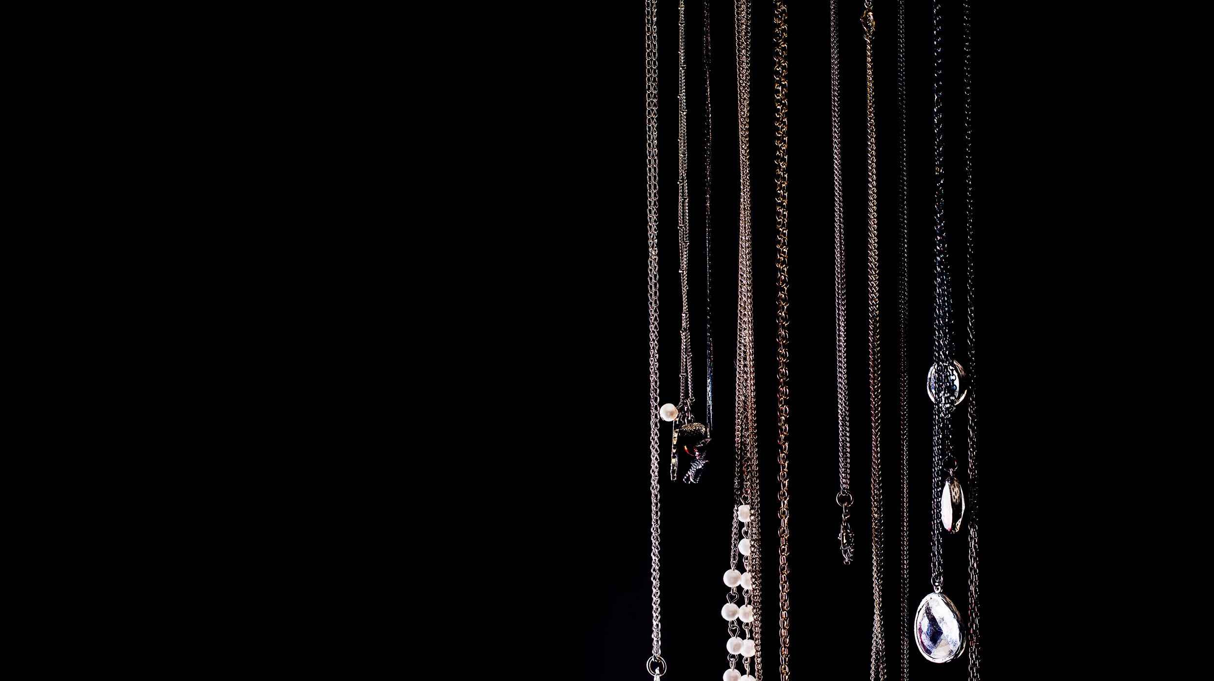 Collection of necklaces with various pendants on a black background