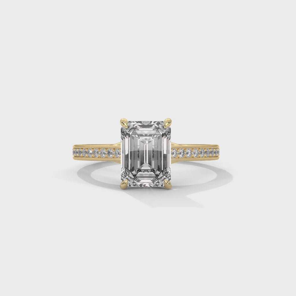 Gold ring with a large baguette-cut diamond and smaller diamonds on the band against a white background, shown from the 360 degree angle.