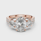 Rose gold ring with a large oval shape diamond in center, 2 round shape diamonds a little bit smaller than center diamond studded on both side of center diamond and some small round diamonds studded after that, is rotating on a white surface.