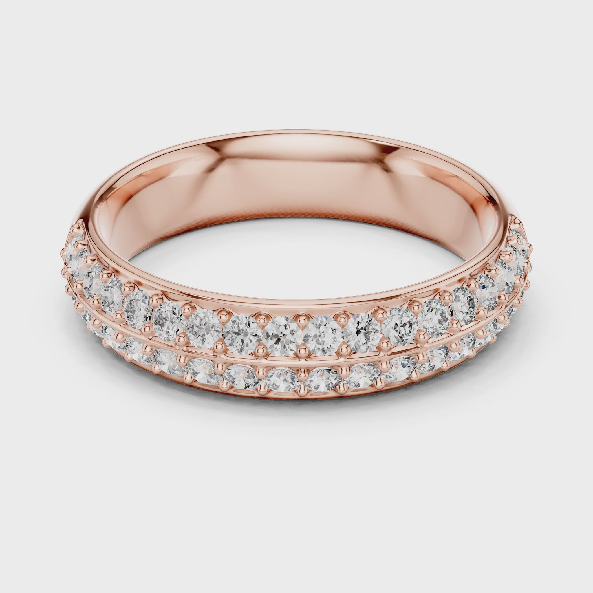 A ring made of rose gold and lab grown diamonds is placed on a white surface and the ring is rotating on the white surface.