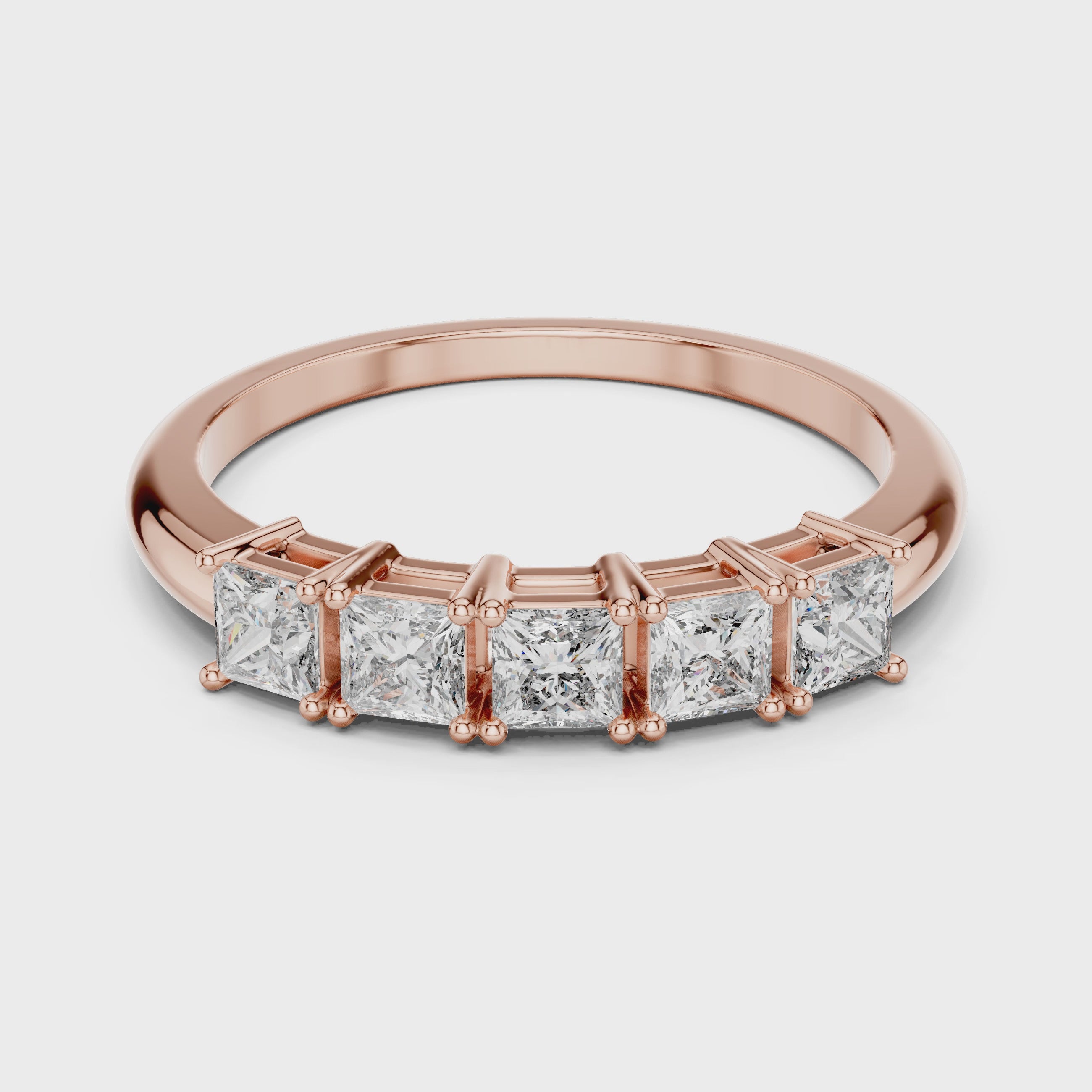 Rose gold ring with clear diamonds is rotating horizontally on a white surface.